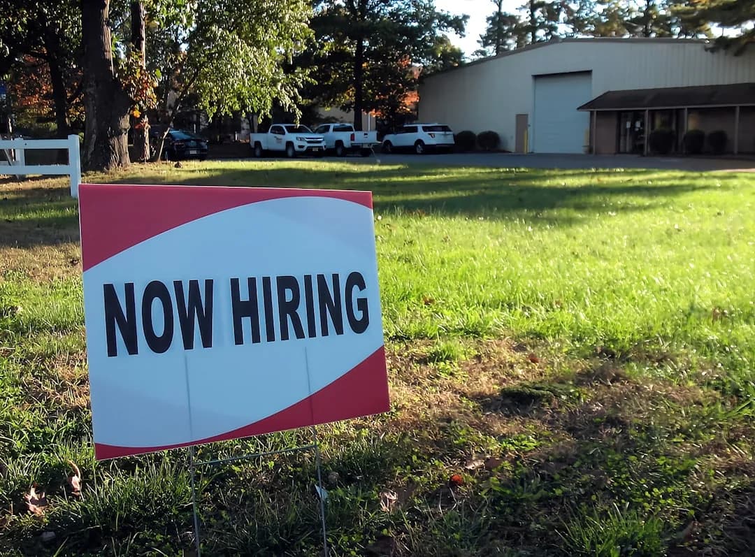 Help wanted sign in a shop window at dusk