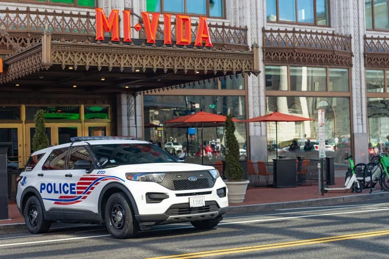A row of uniformed National Guard members standing on a city sidewalk near a metro station entrance