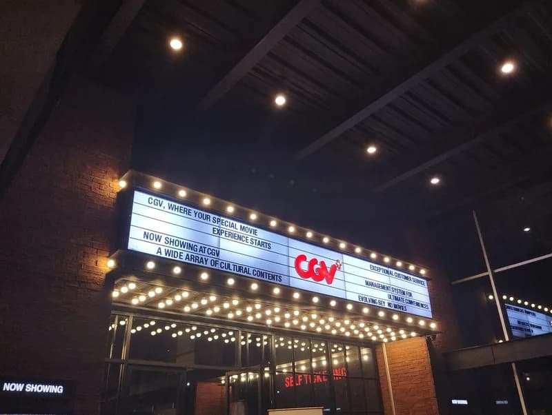A cinema marquee at night lit up outside a busy theater entrance